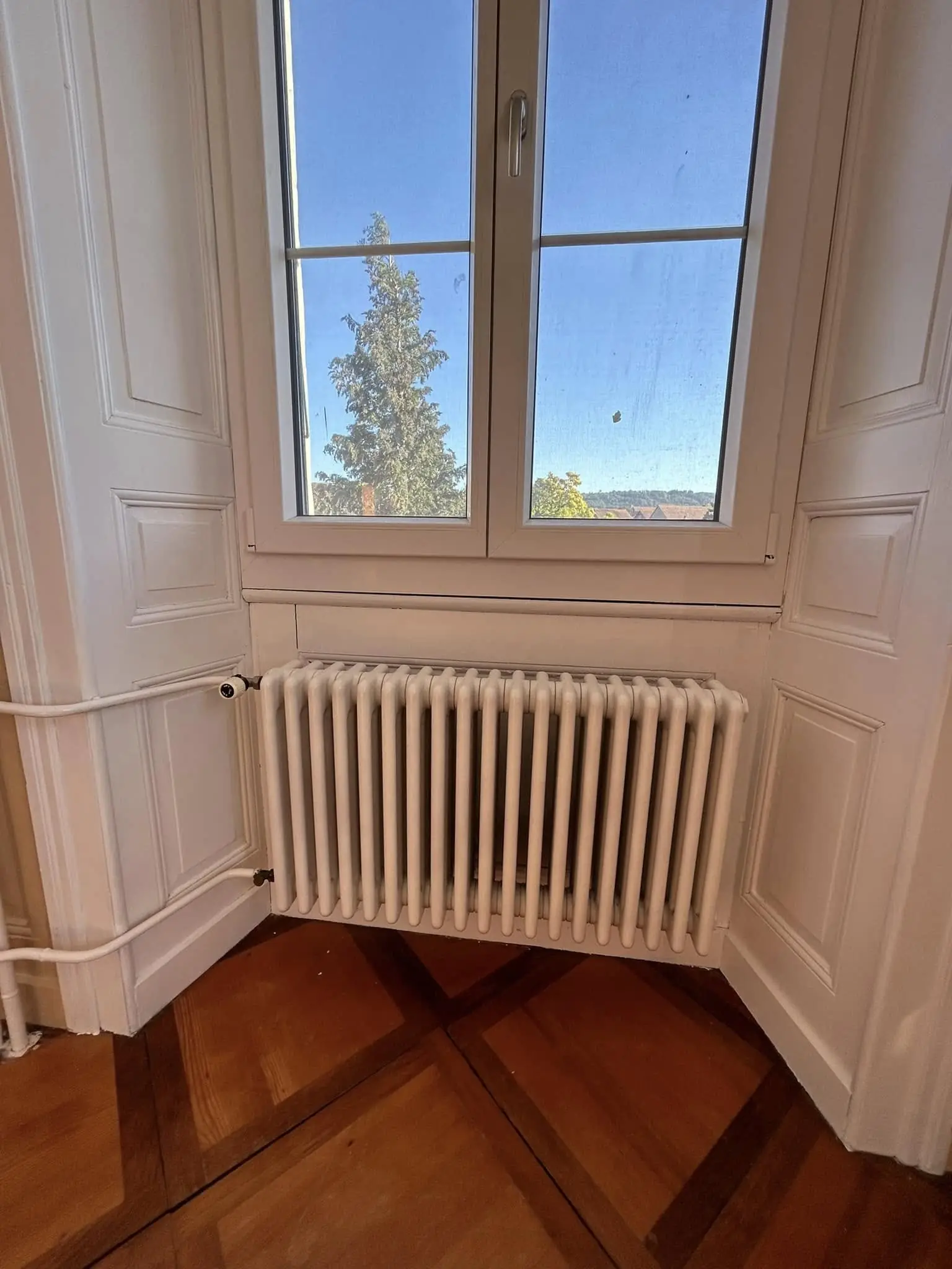 Boiseries de la fenêtre laquées en blanc, radiateur à colonnes et conduite repeints
