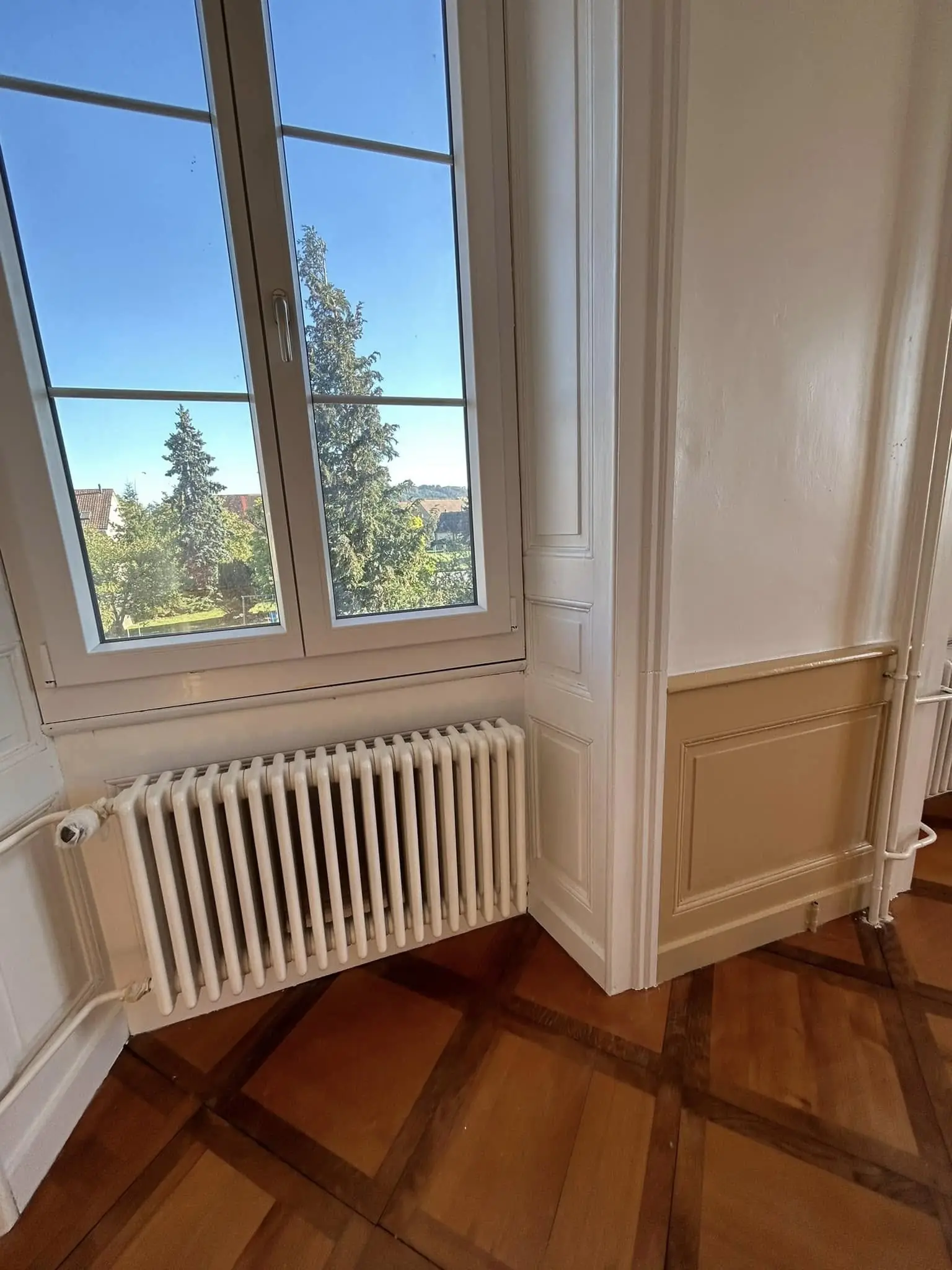 Encadrement de fenêtre laqué en blanc au-dessus d'un soubassement repeint en beige