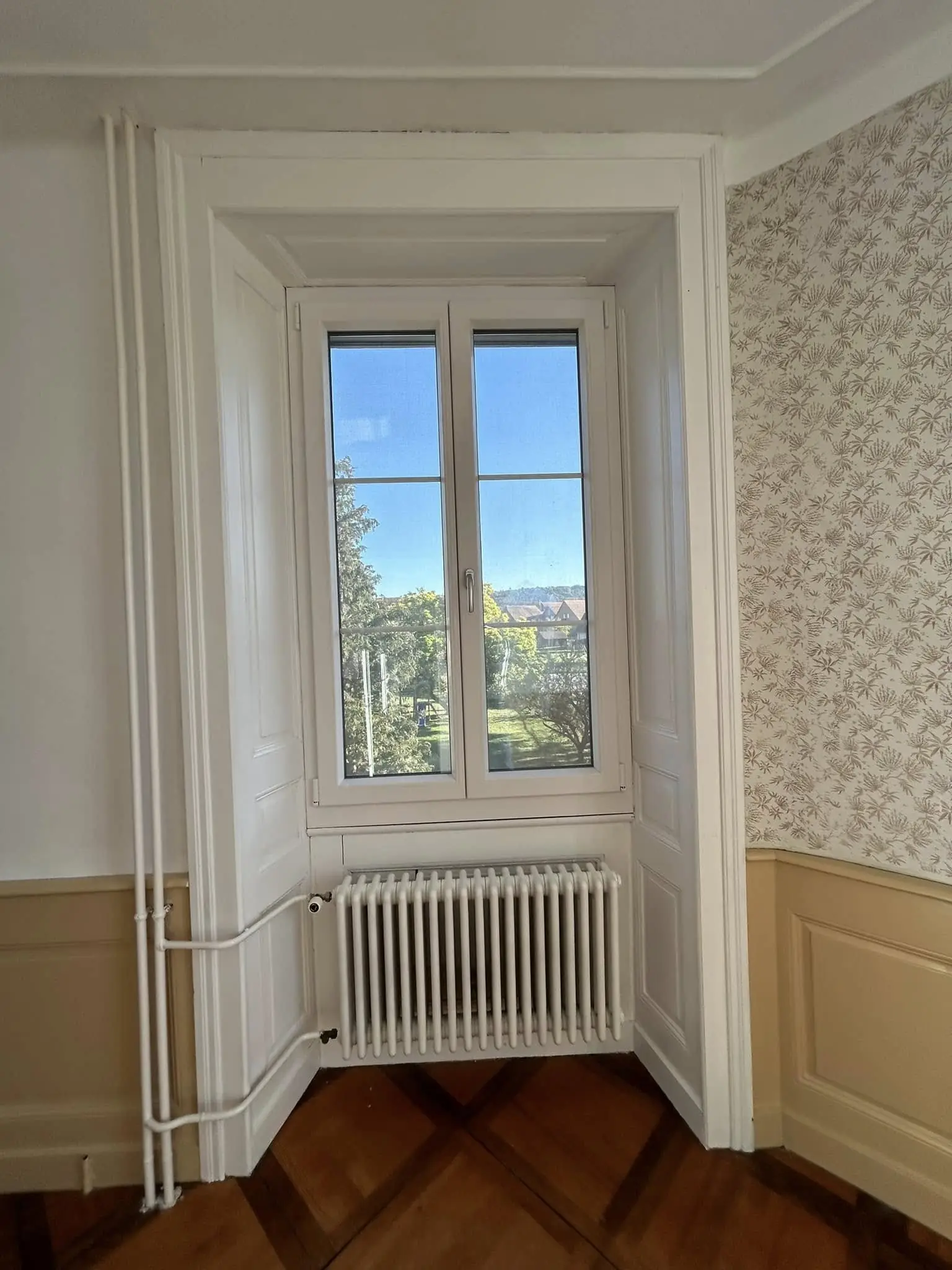 Boiseries de l'embrasure laquées en blanc à côté du papier peint conservé
