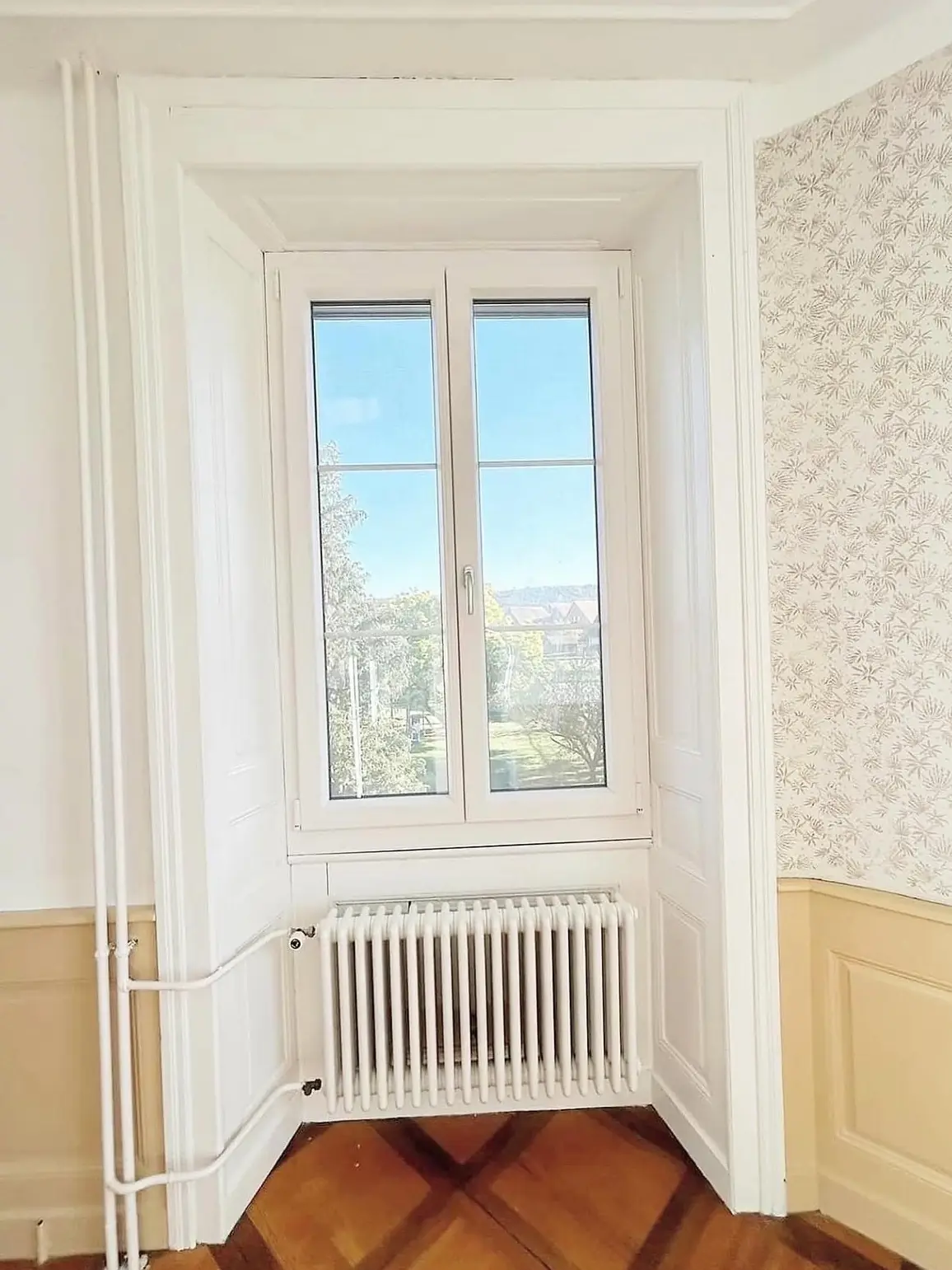 Radiateur repeint en blanc sous une embrasure de fenêtre reprise en peinture
