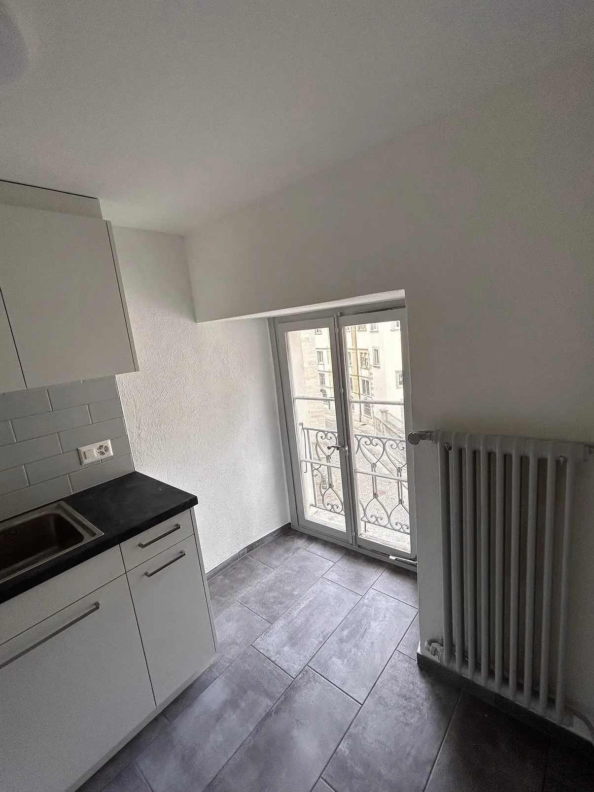 Cuisine aux murs repeints en blanc, radiateur et porte-fenêtre repeints, à Estavayer-le-Lac