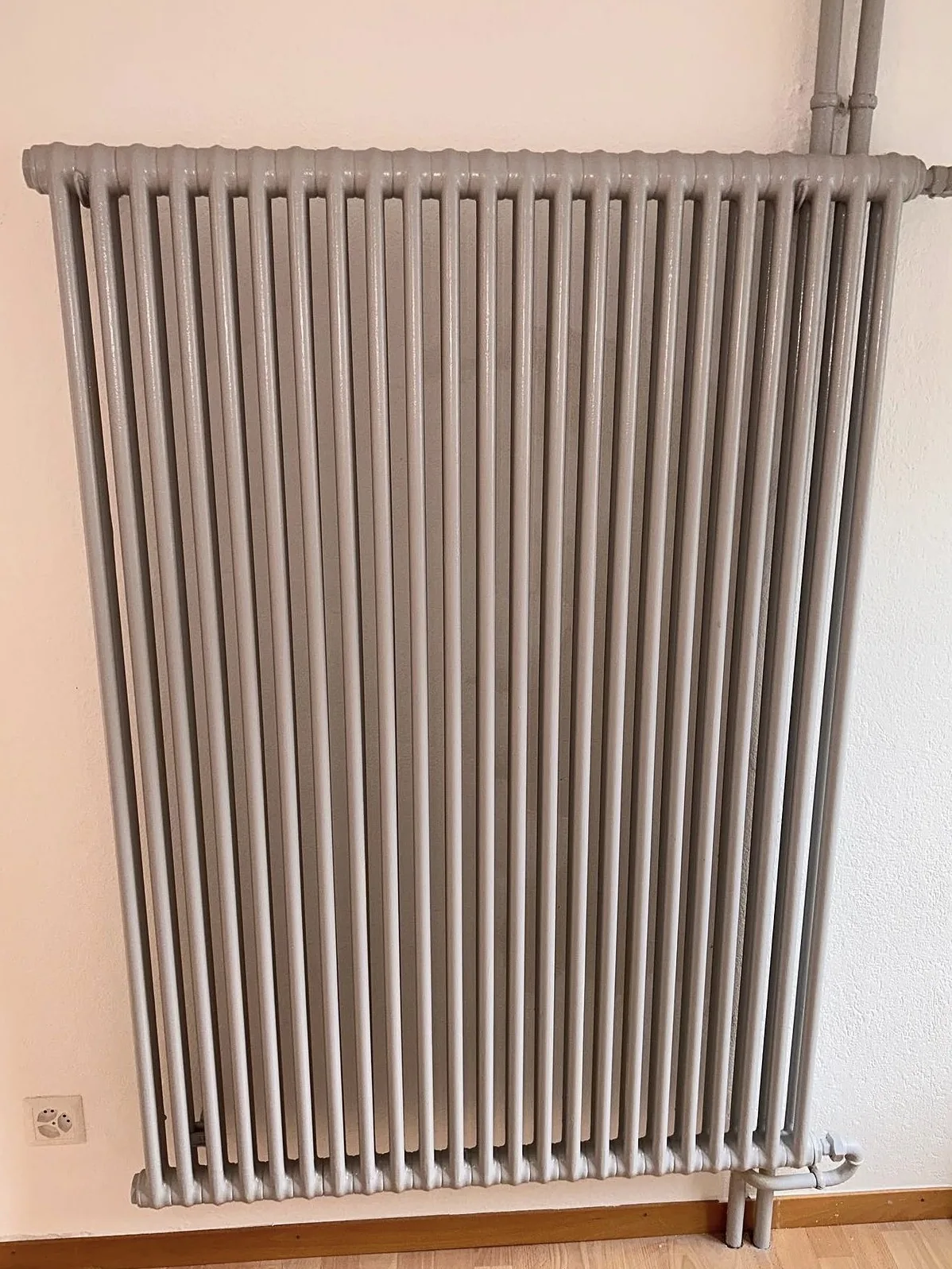 Radiateur à colonnes repeint en gris clair, à Estavayer-le-Lac