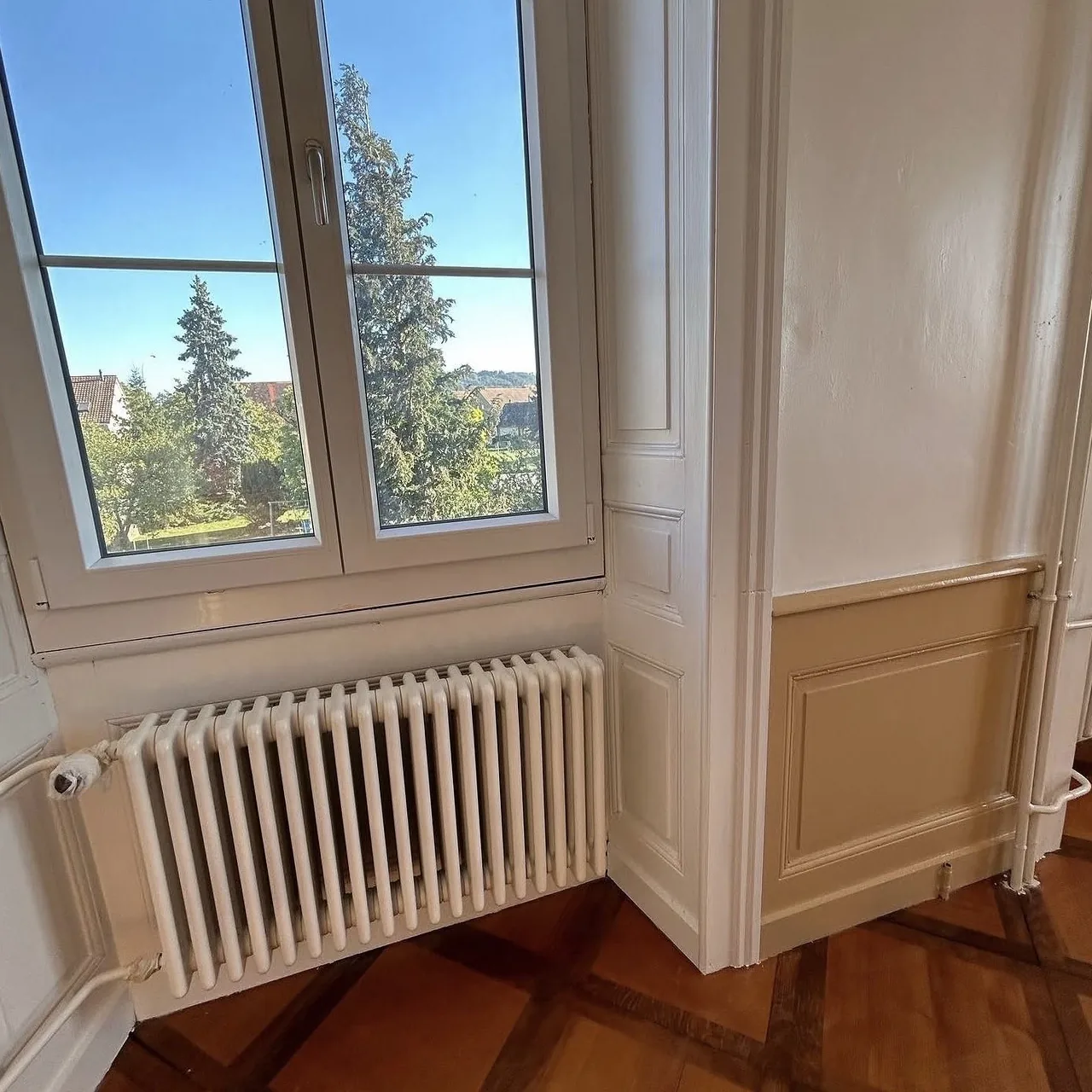 Embrasure de fenêtre et radiateur repeints en blanc, lambris beige, à Corcelles-près-Payerne