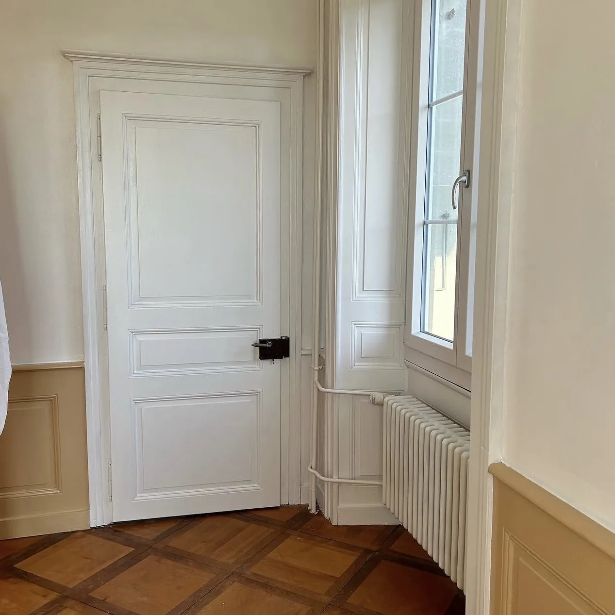 Porte à panneaux et radiateur en fonte repeints en blanc, à Corcelles-près-Payerne