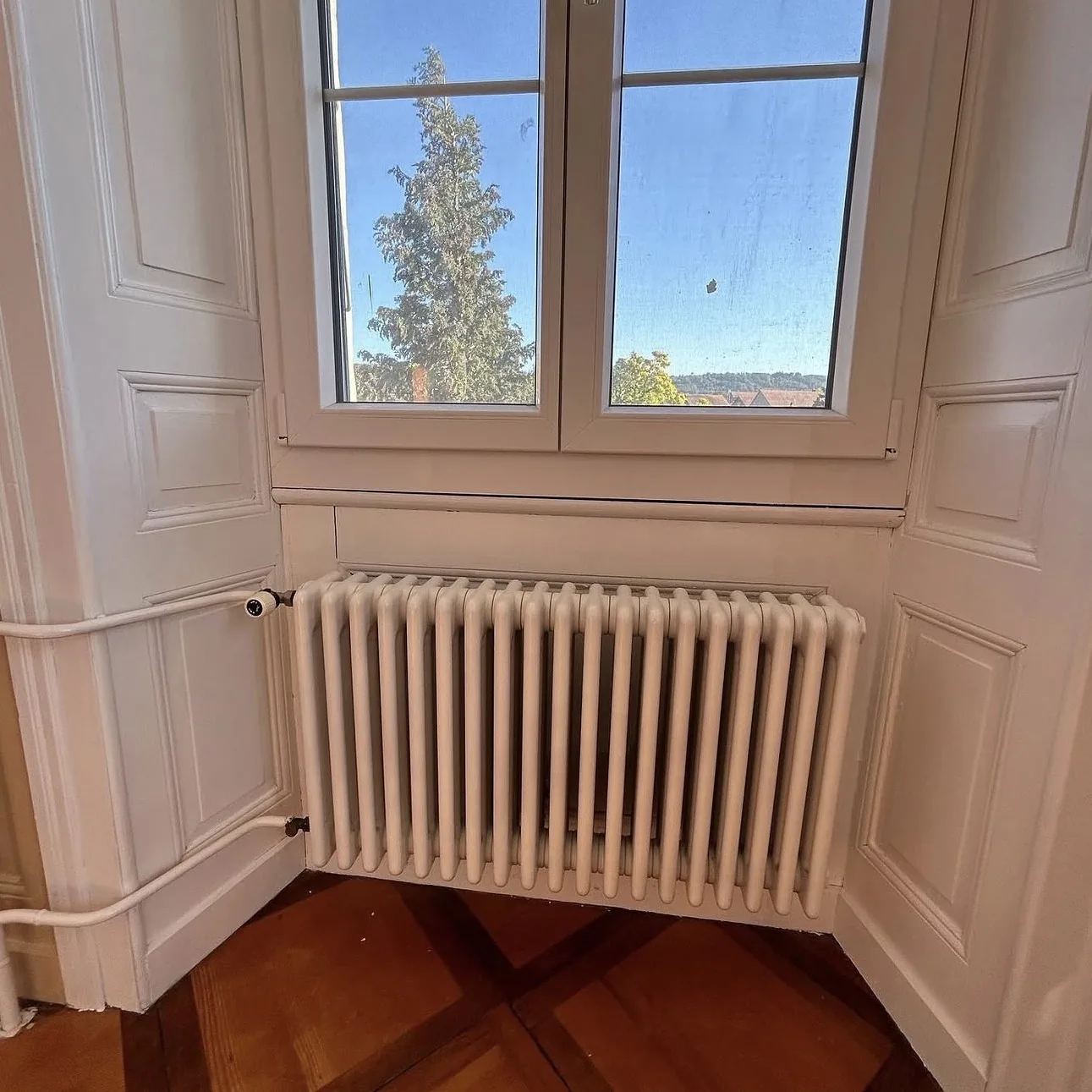 Radiateur et embrasure de fenêtre repeints en blanc, lambris beige, à Corcelles-près-Payerne