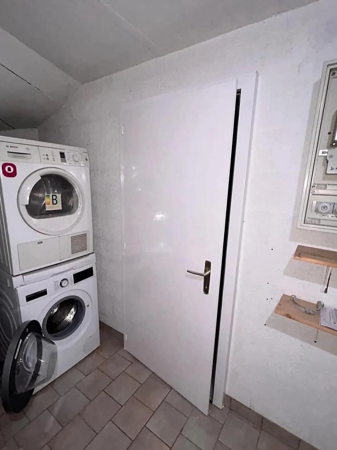 Murs et plafond de la buanderie repeints en blanc autour de la porte et du tableau électrique