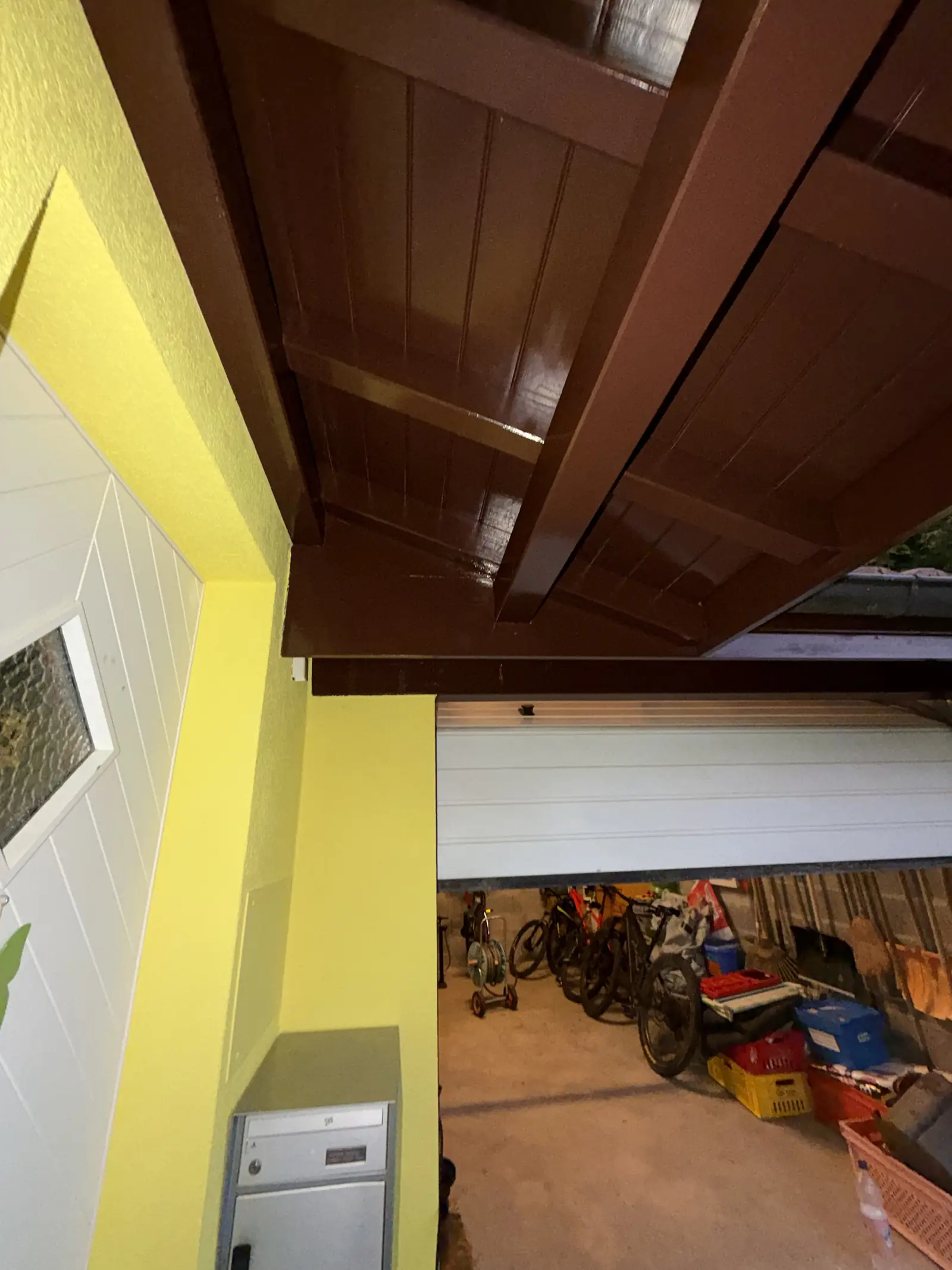 Lambris et chevrons de l'avant-toit repeints en brun au-dessus du garage