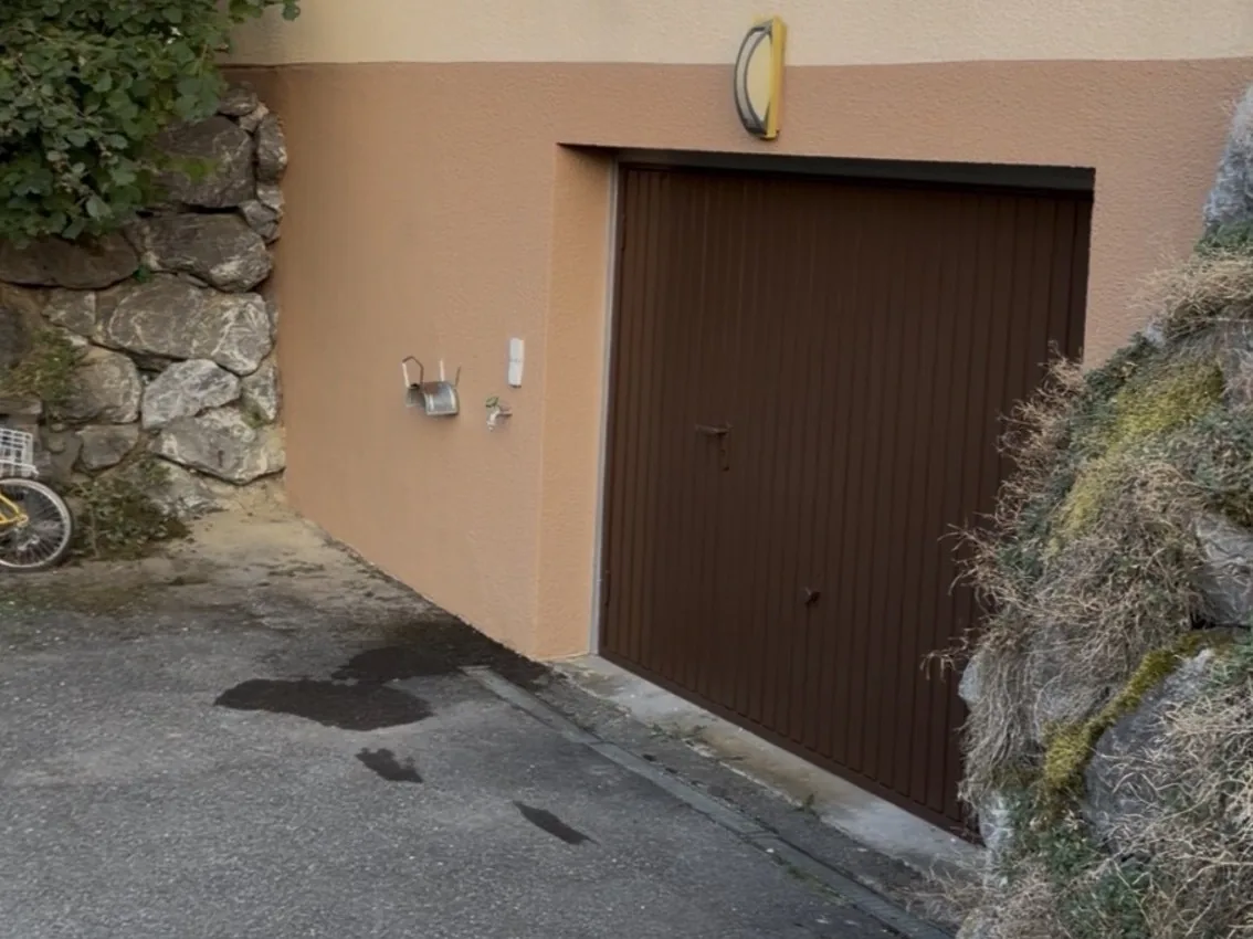 Après : Façade repeinte en deux couleurs, jaune pâle et terre cuite. Porte de garage poncée, traitée et repeinte en brun.