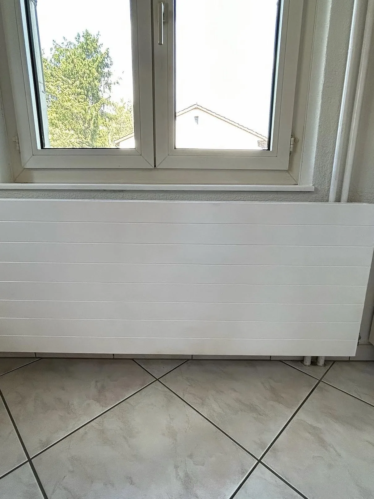 Radiateur sous fenêtre repeint en blanc, mur repeint, à Estavayer-le-Lac