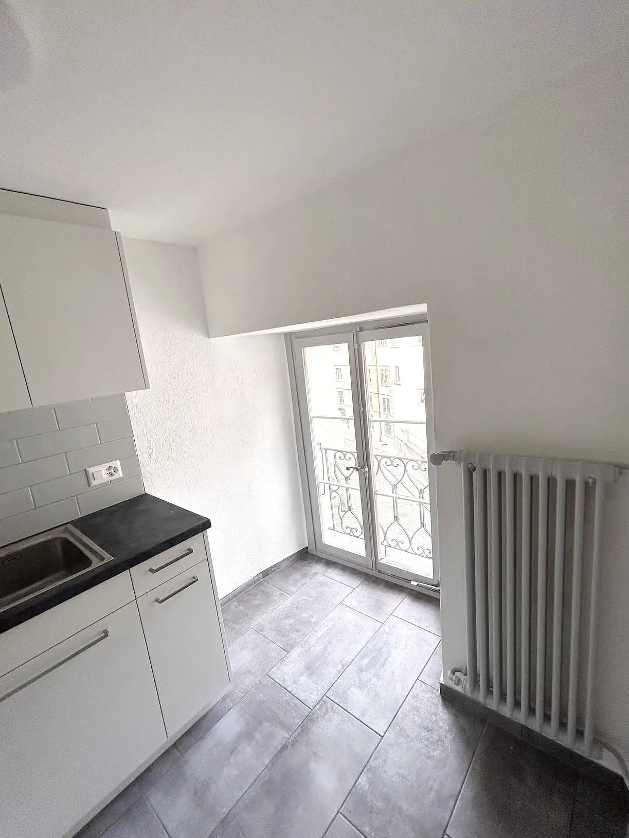 Murs et plafond de la cuisine repeints en blanc, radiateur et porte-fenêtre repris