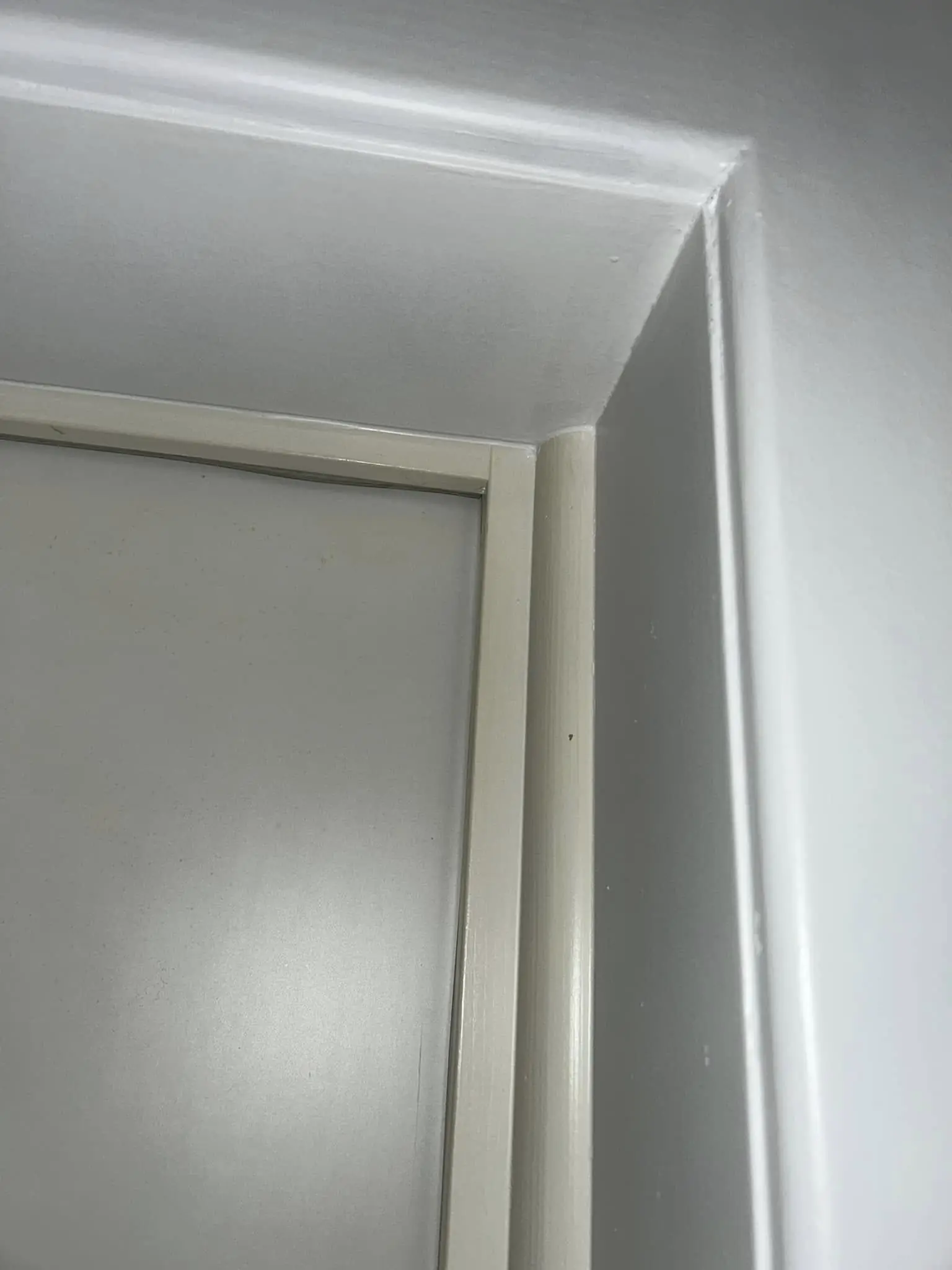 Encadrement de porte laqué en blanc, arête du mur lissée à l'enduit puis peinte